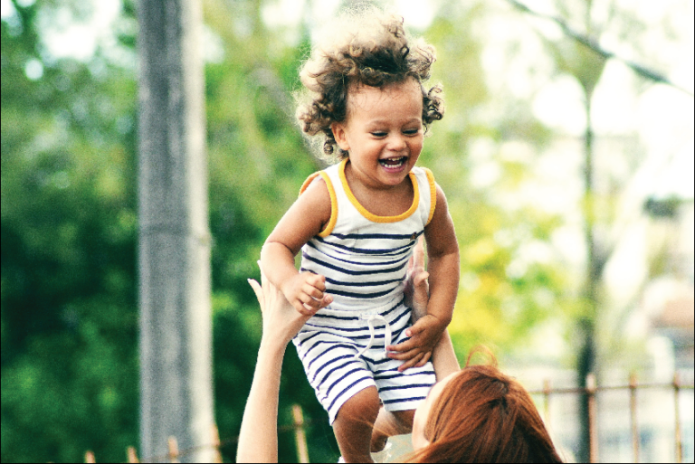 woman tossing smiling child and catching her