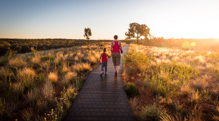 womand and child walking on brightly lit park path