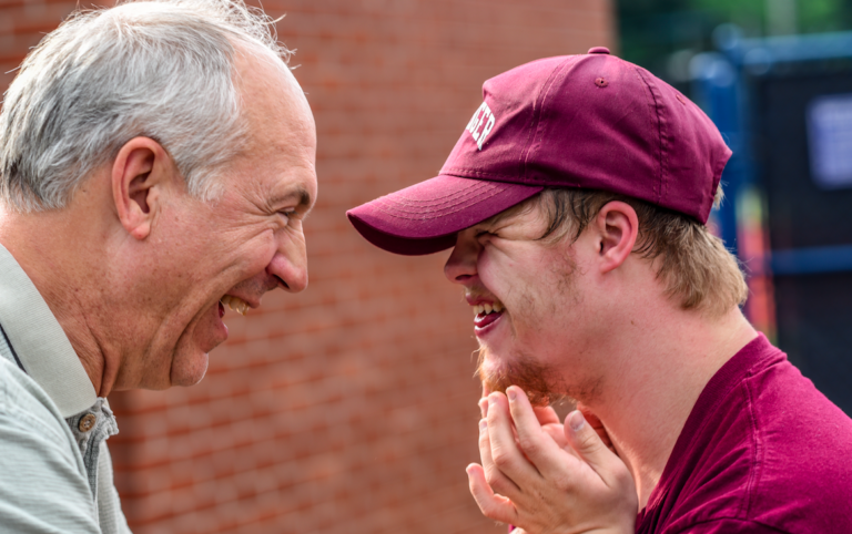 elderly man and younger man looking at eachother laughing