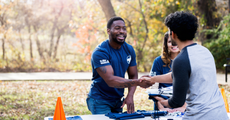 Man shaking hand with another man as he hands out swag