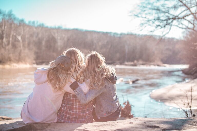 three women hugging on bank of river
