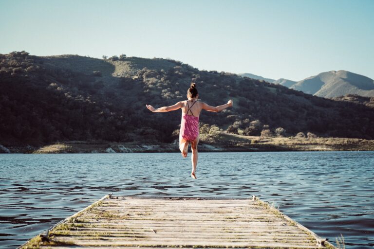 girl jumping off lakeside dock