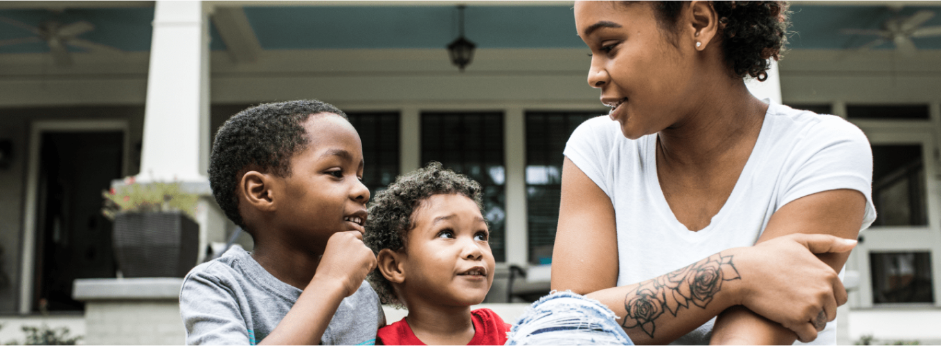 woman and children sitting in front of house