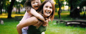 smiling woman giving piggy back ride to smiling child