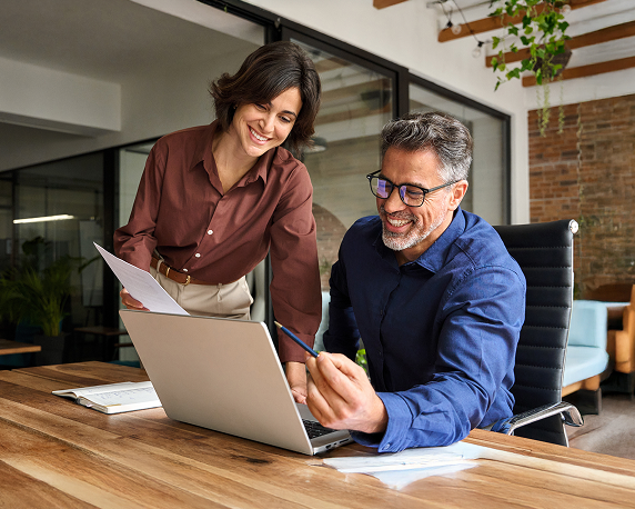 two coworkers smiling while looking at computer screen